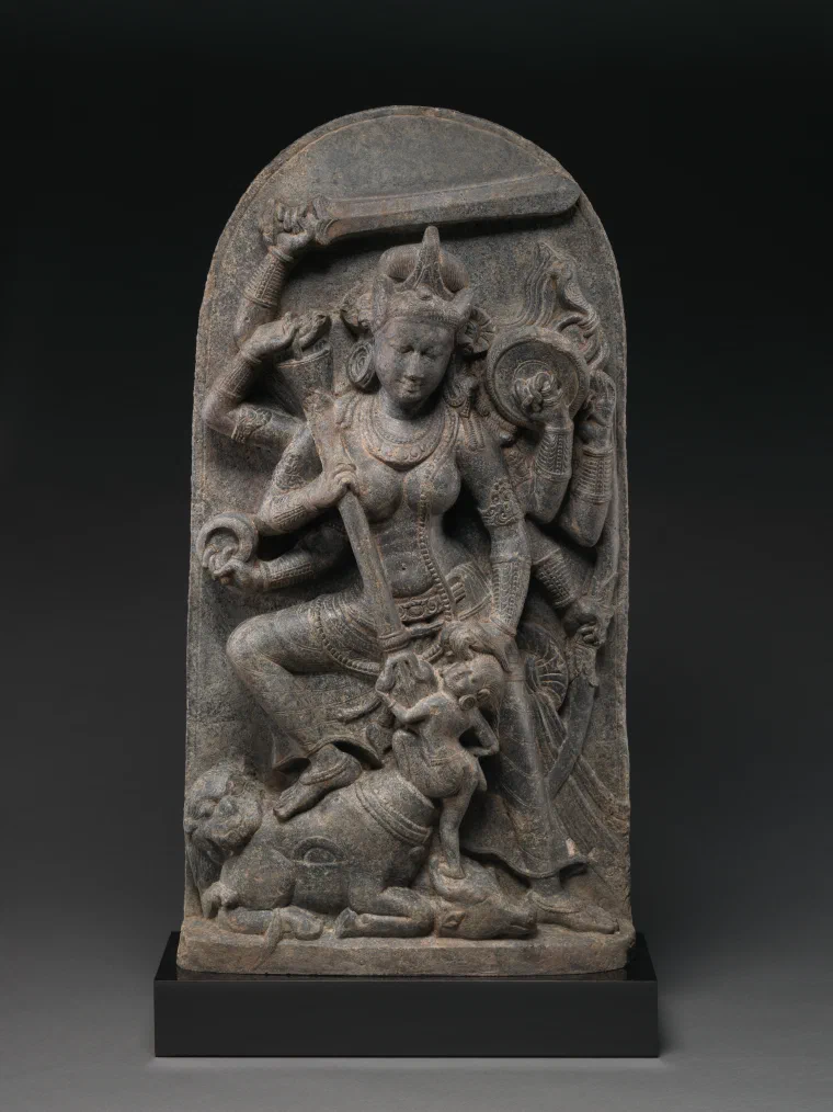 Dark stone sculpture of the many-armed goddess Durga defeating the buffalo demon Mahisha